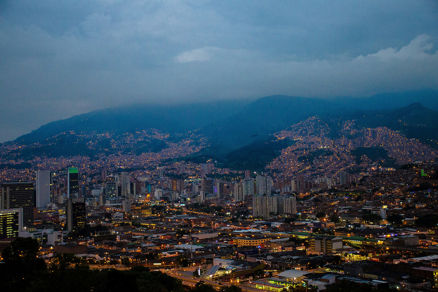 Night view of Medellín, Colombia, with the city's skyline and hills lit up, showcasing a vibrant urban landscape.