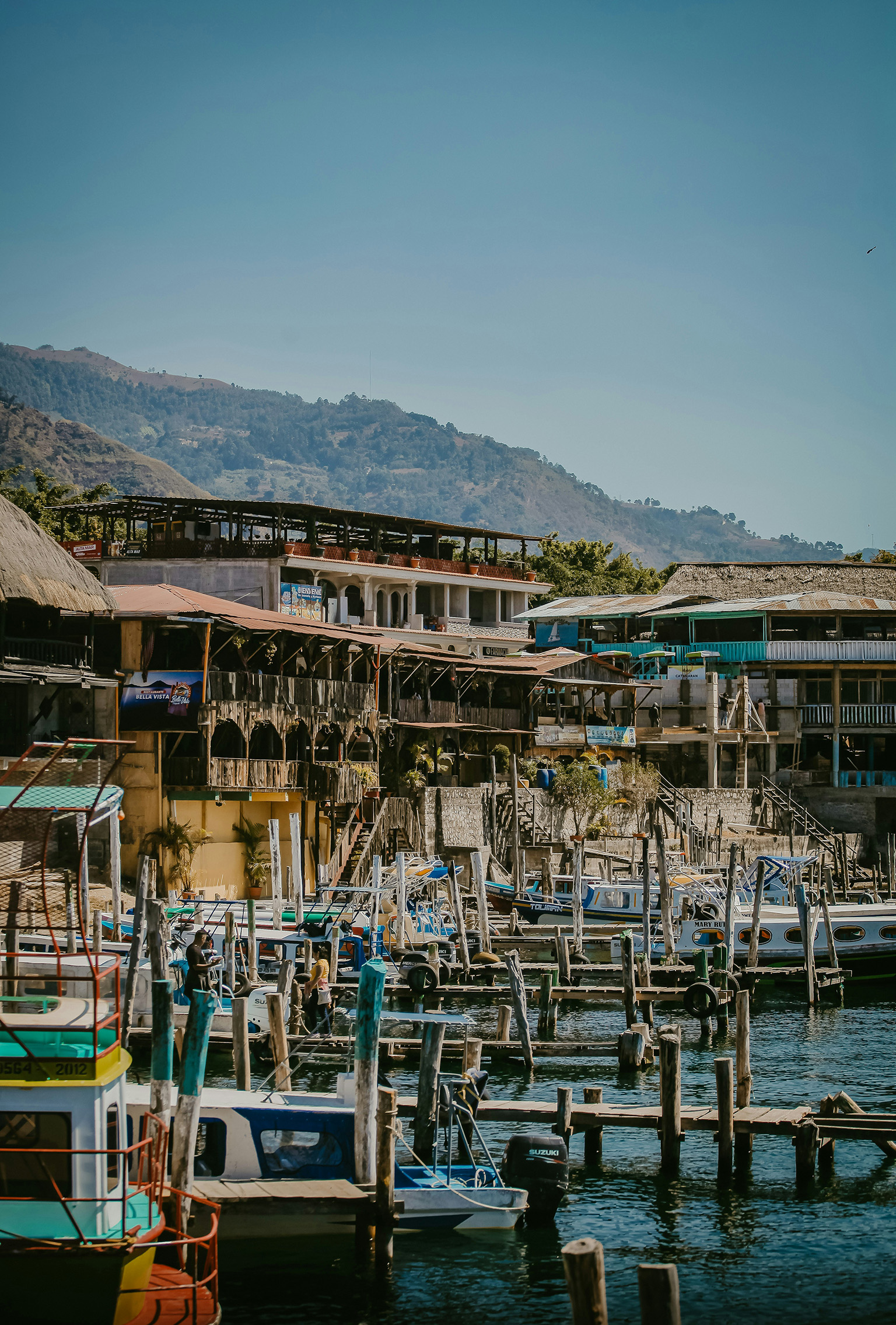 Dock area on Lake Atitlán with boats and volcanoes in the background.