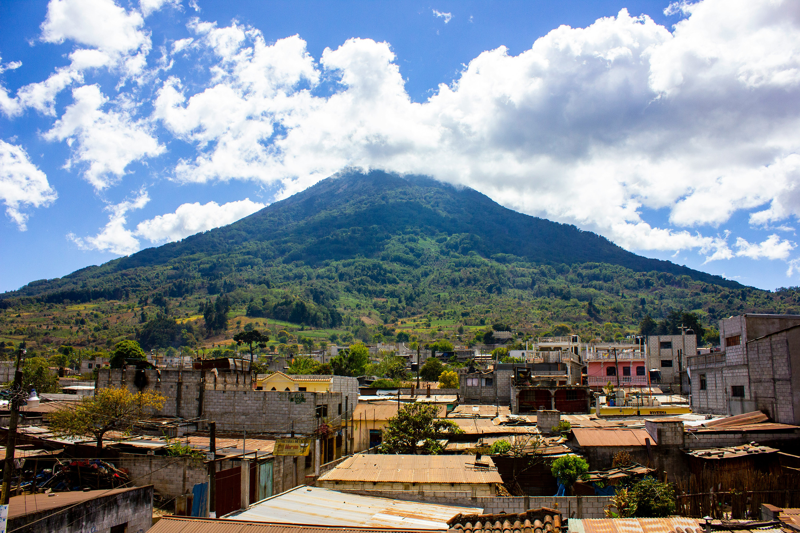 Scenic town in the foreground with a towering volcano in the background, showcasing the natural beauty of Guatemala.