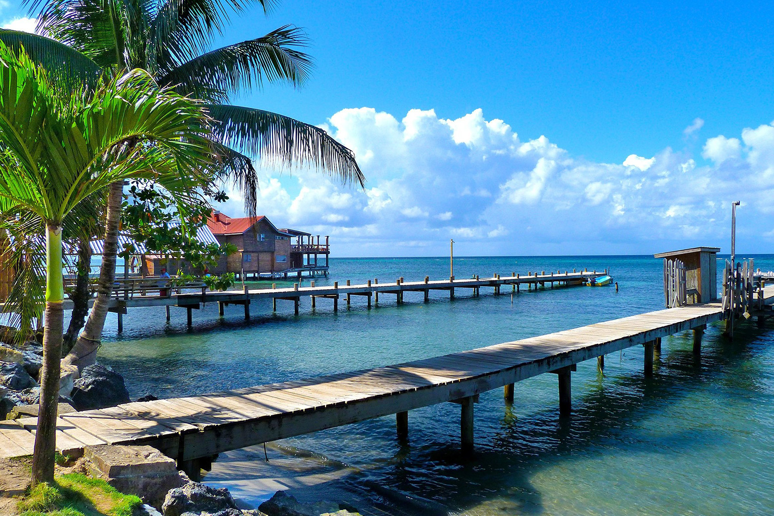 Crystal-clear waters, a wooden dock, and a bright blue sky in Honduras.