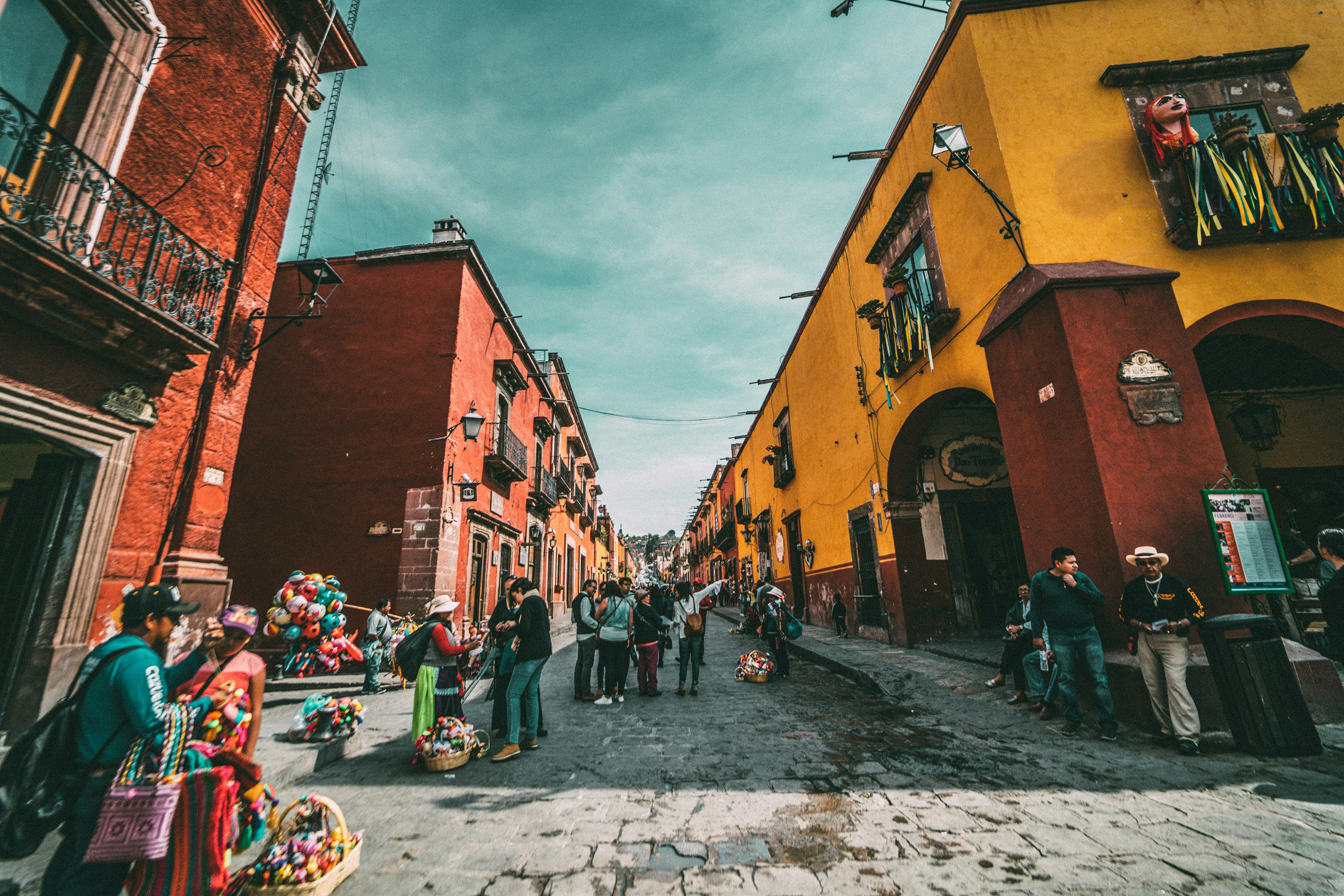 A busy Mexican street filled with colorful shops and bustling activity, capturing the lively atmosphere of a popular town, representing the dynamic vibe of life in Mexico.
