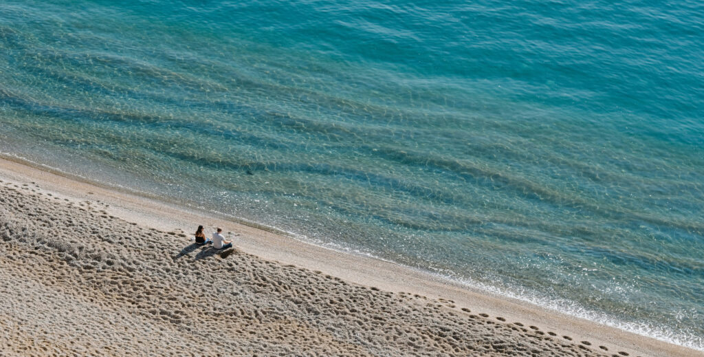Couple sitting on the beach highlighting their journey to Latin America and discussing "about us'
