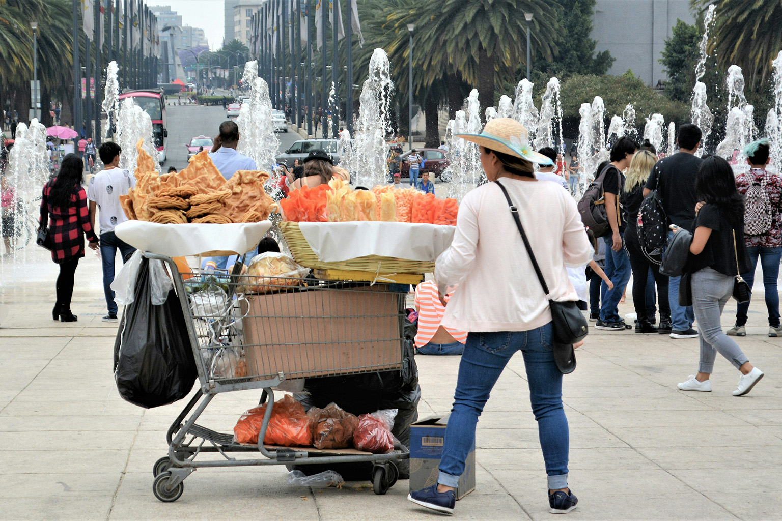 Snack vendor in a colorful outdoor plaza in Mexico surrounded by locals and tourists.