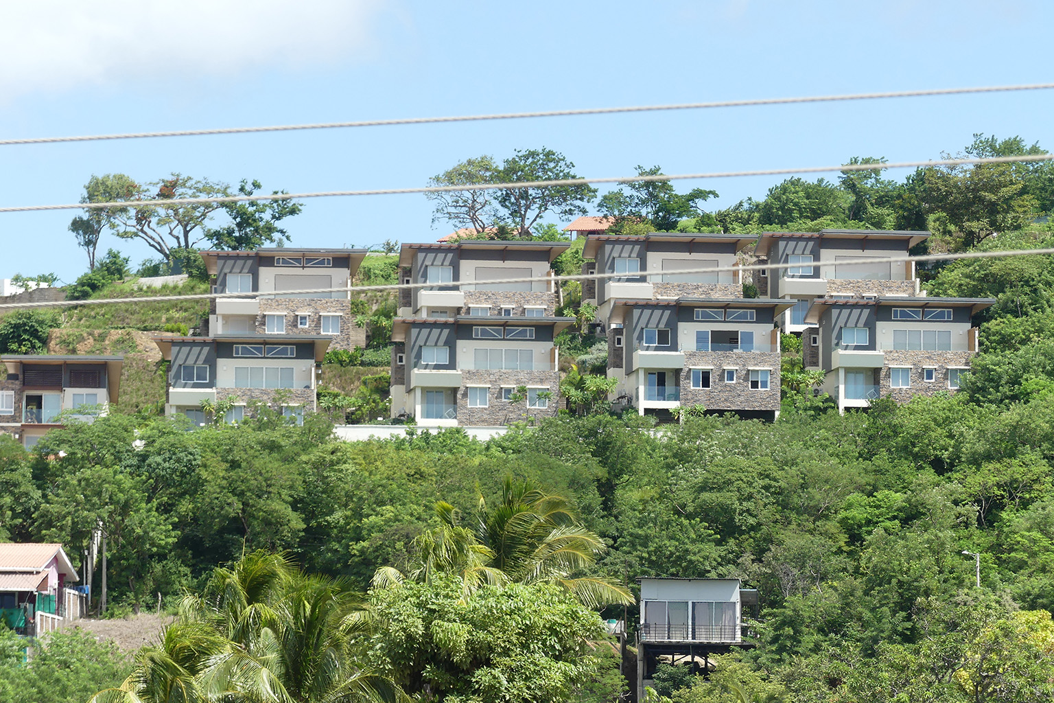 Houses on a hill surrounded by dense forest in San Juan del Sur, highlighting the area's natural beauty and tranquil living environment.