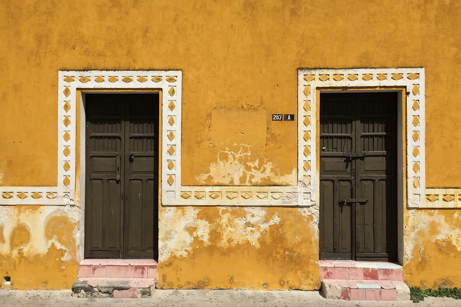 Close-up of an old, colorful building with intricate wooden doors, Mexico.