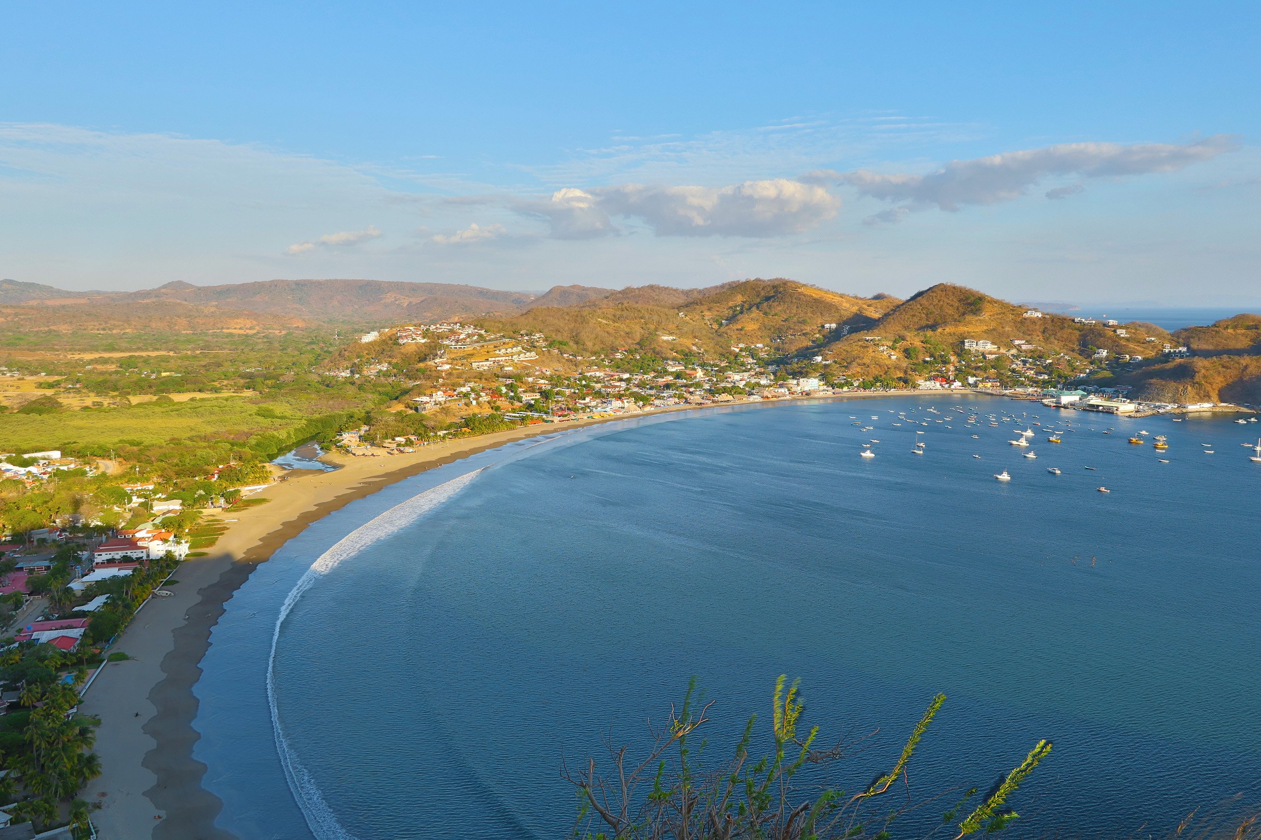 Aerial view of San Juan del Sur bay with boats and surrounding mountains, highlighting the scenic beauty of the area.