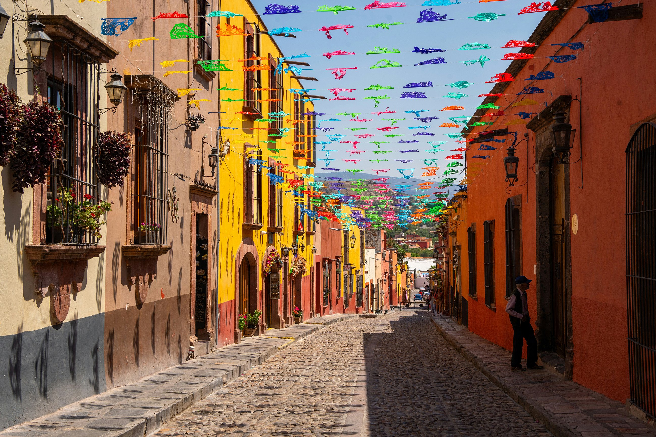 Cobbled street lined with colorful buildings and flags in San Miguel de Allende, Mexico.