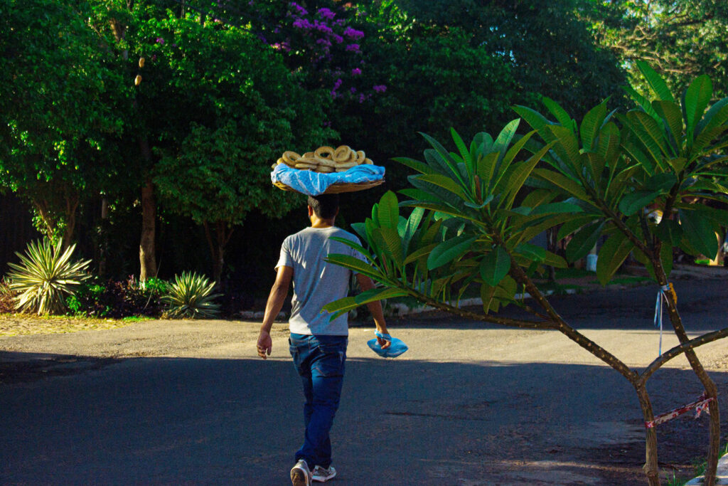 Paraguayan man walking with a basket of chipa on his head