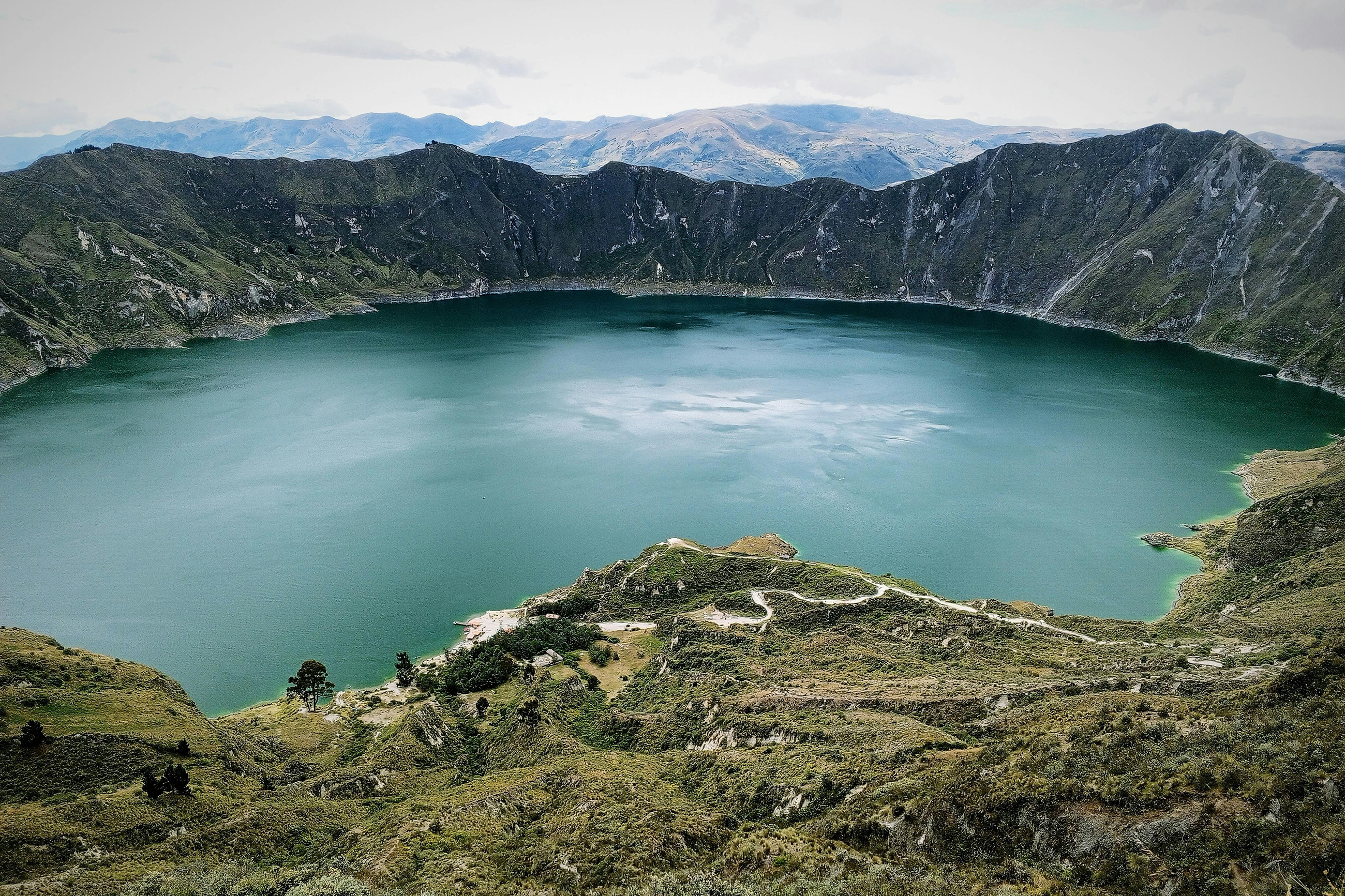 A panoramic view of Quilotoa Crater Lake in Ecuador, with its vibrant turquoise waters surrounded by rugged mountain landscapes.