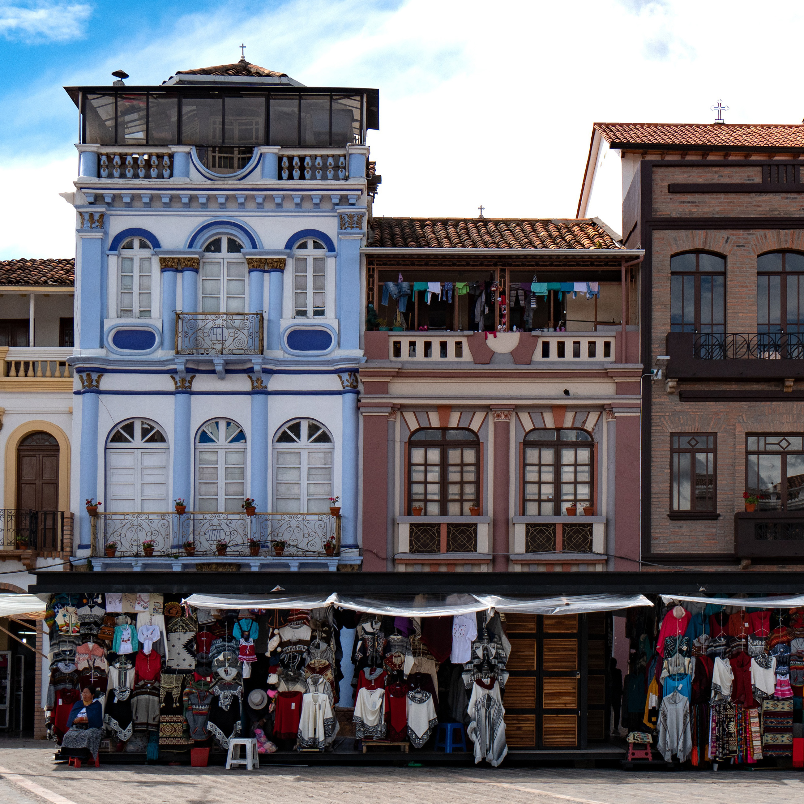 A vibrant traditional street in Ecuador, lined with colorful market stalls and handcrafted goods.