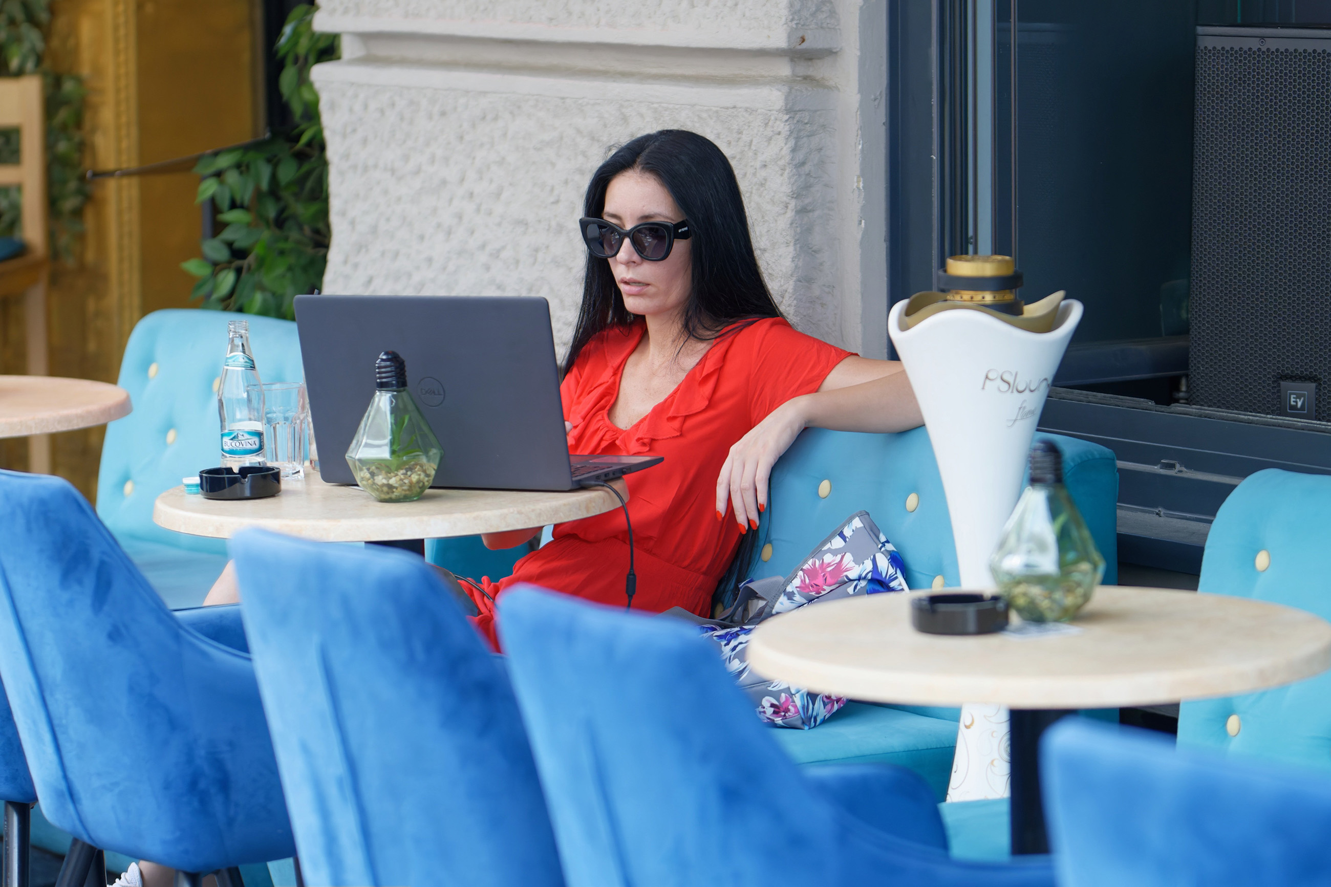 A businesswoman working remotely on her laptop at an outdoor cafe, enjoying flexible work arrangements.