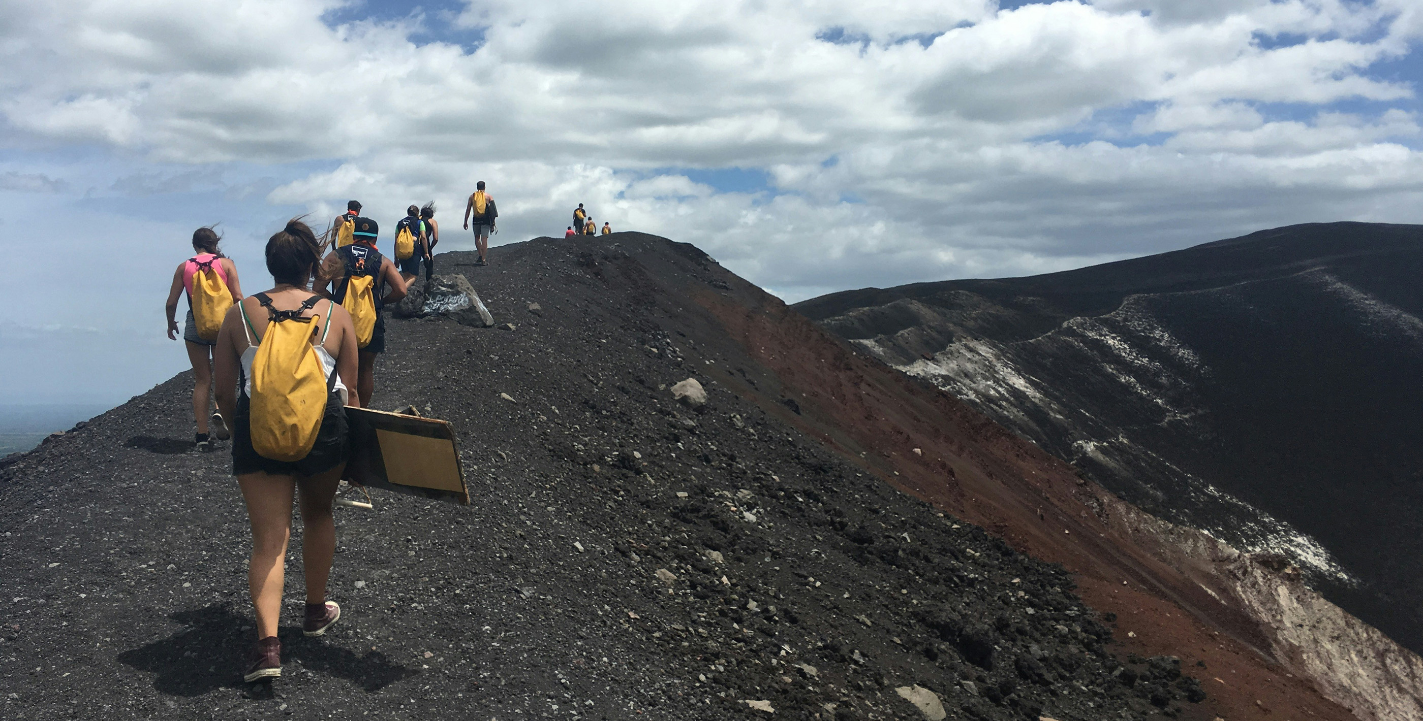 People sandboarding on a volcanic slope at Sendero al Cráter, Nicaragua