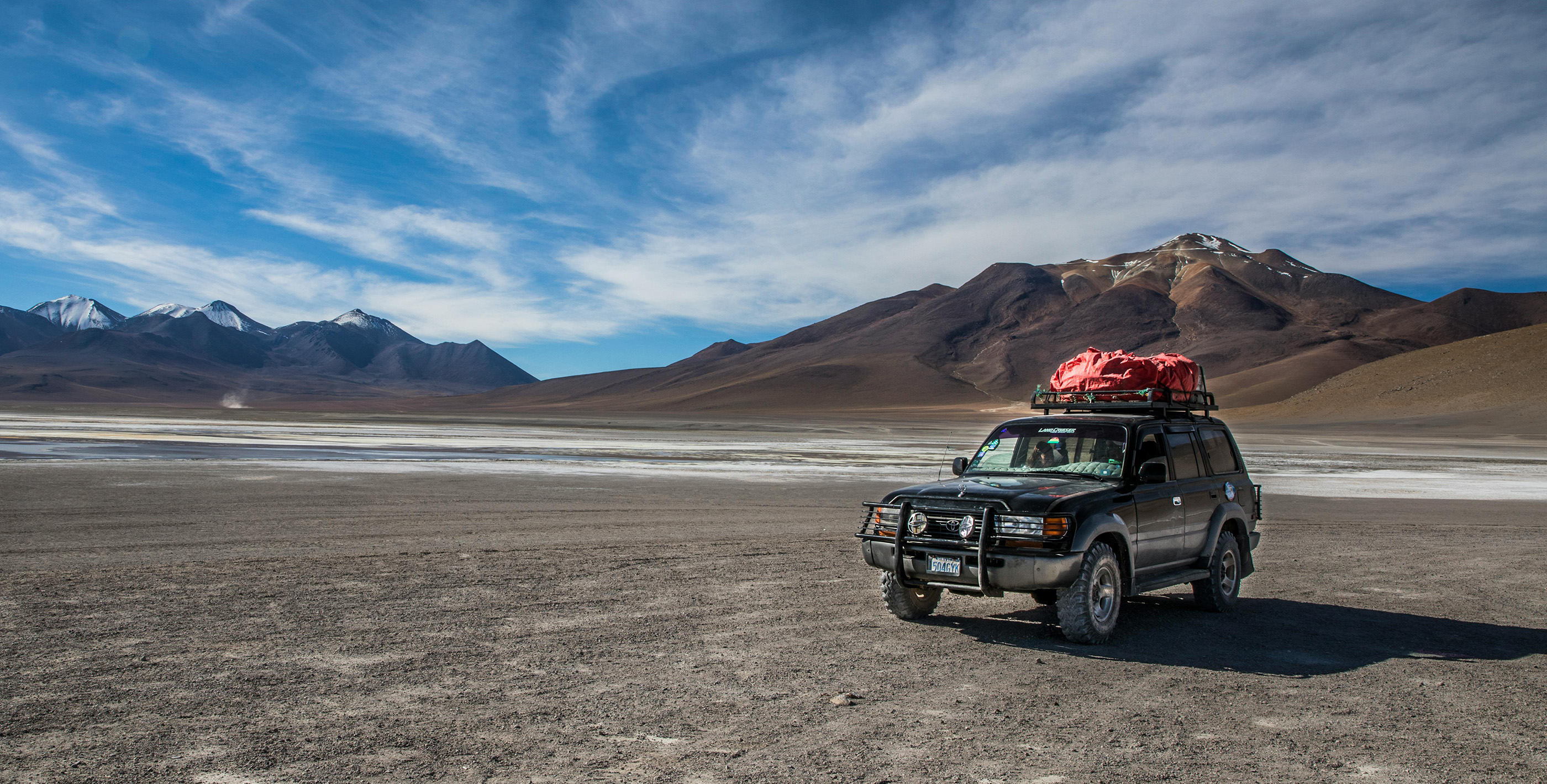 All-terrain truck crossing Bolivia’s barren highlands with mountains in background