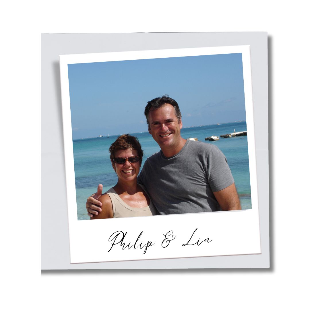 Couple smiling at the camera with the ocean in the background, living their dream life in Latin America
