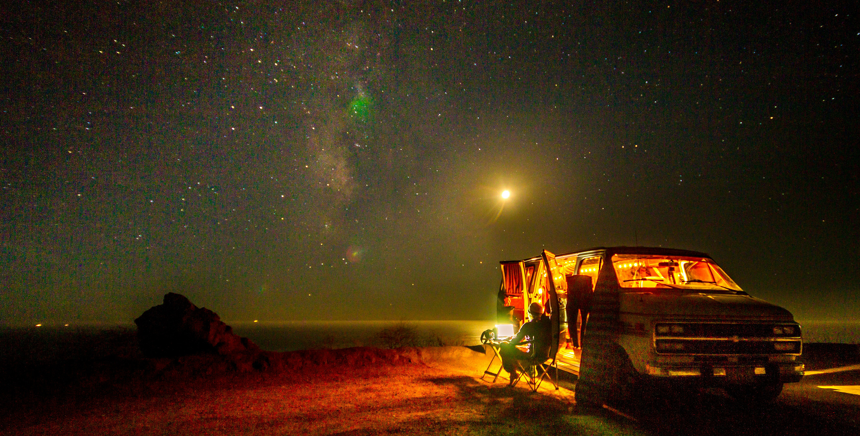 Remote work setup in a van at night with a laptop and cozy lights, perfect for digital nomads embracing a mobile lifestyle