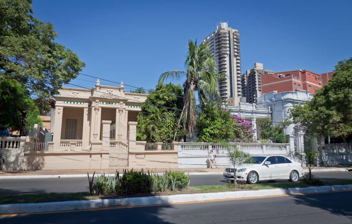 Street in Asunción with historic grand homes and modern buildings in the background, reflecting the city's mix of old and new architecture.