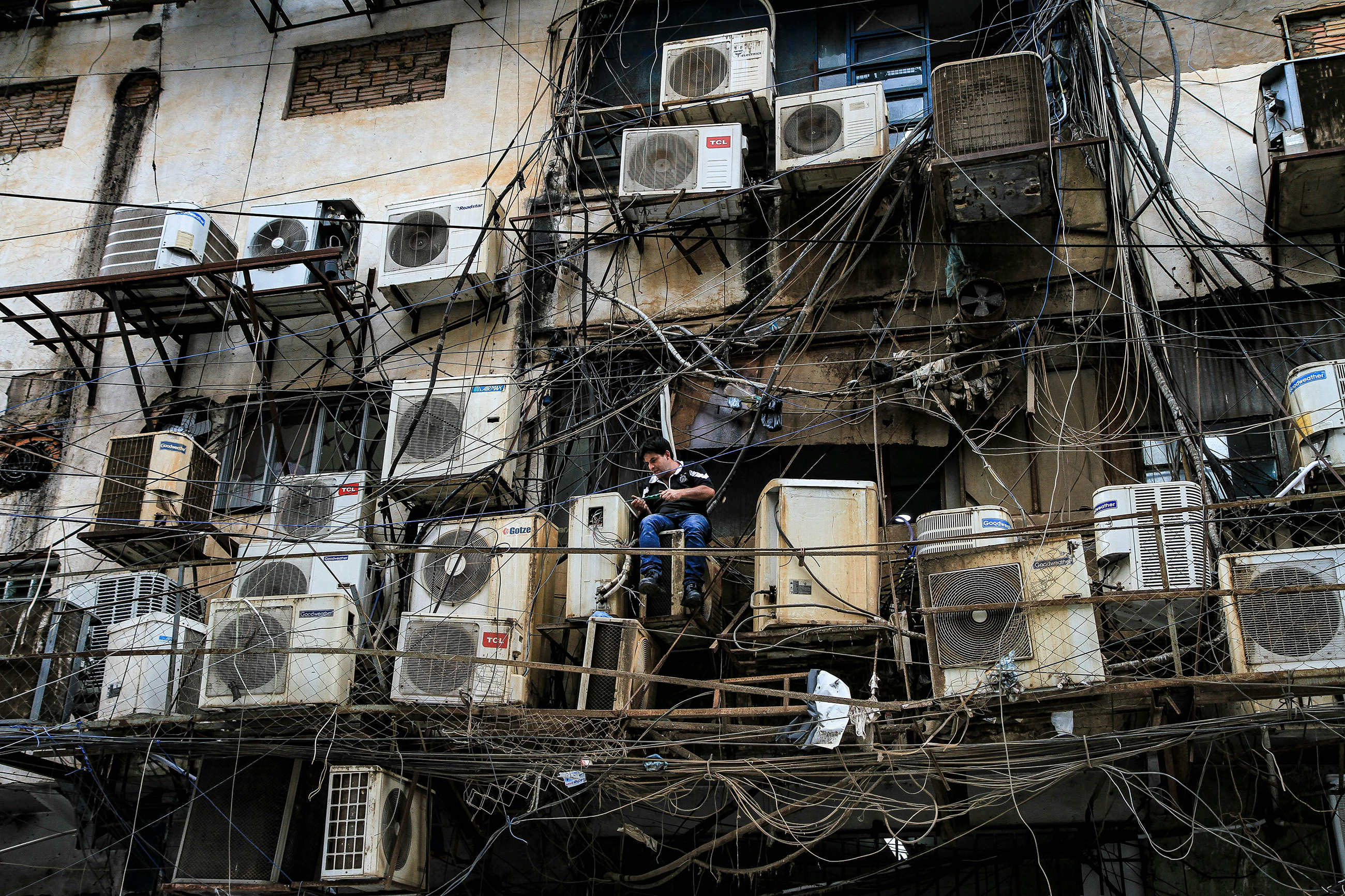 asuncion-building-maintenance-with-tangled-cables-paraguay Man repairing tangled cables and air conditioning units on a building in Asunción