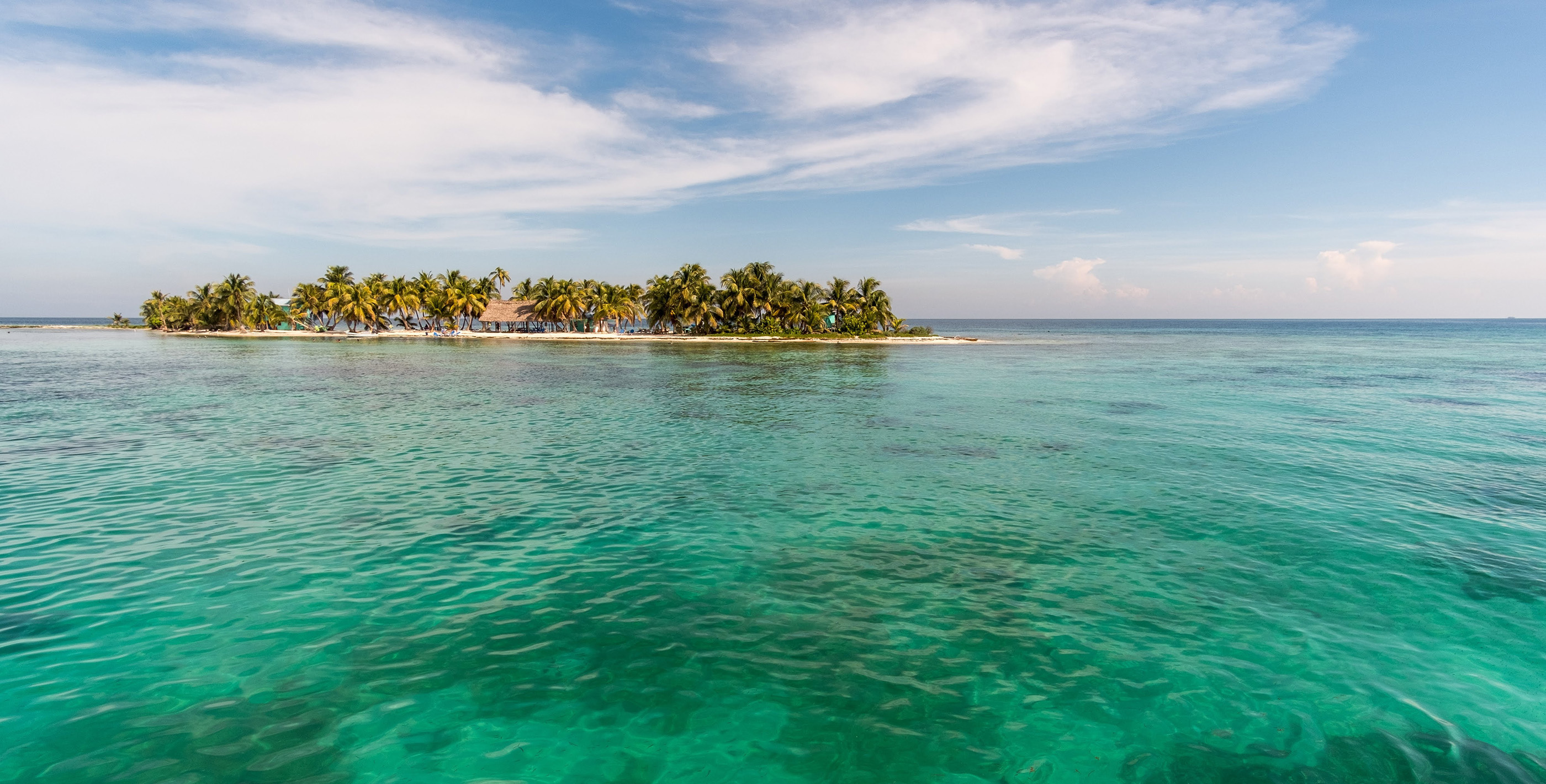 Turquoise water and small tropical island in coastal vs inland Belize
