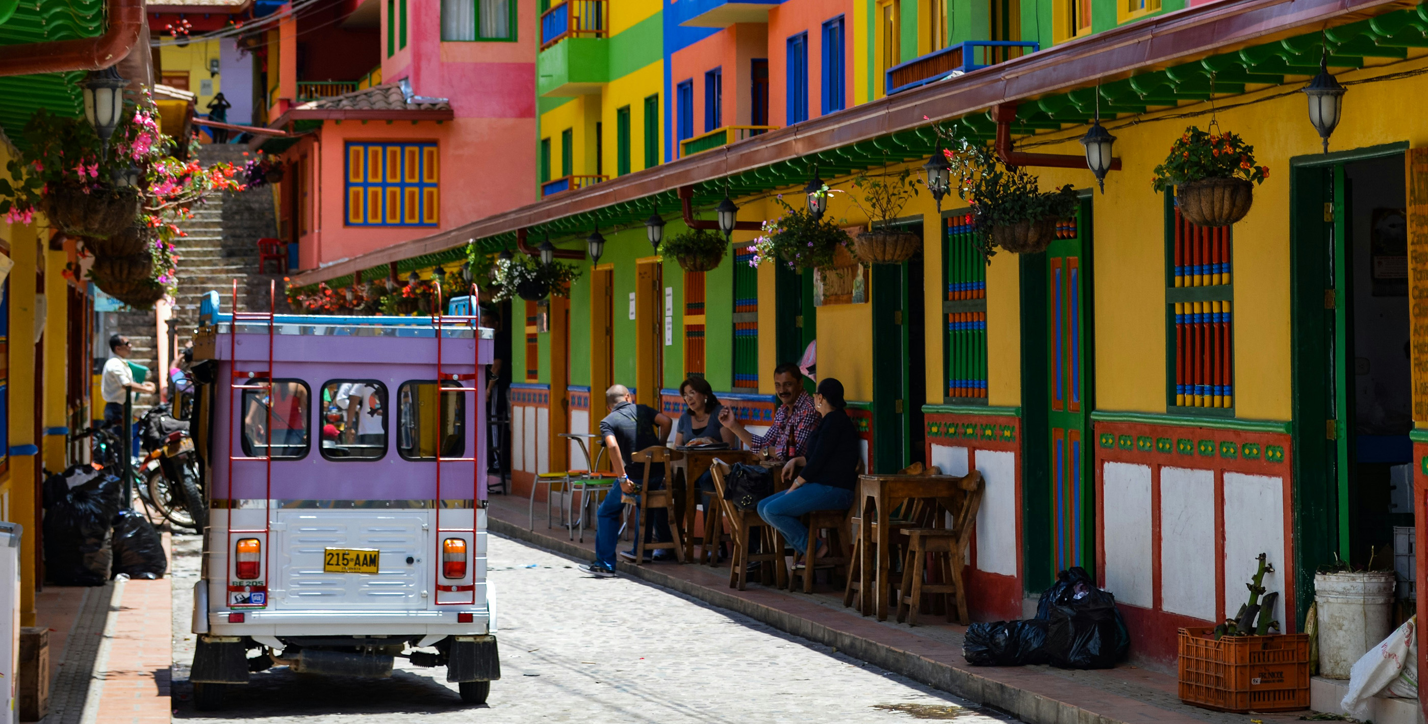 A street lined with vibrant colonial-style buildings and people enjoying a sidewalk café in Colombia.