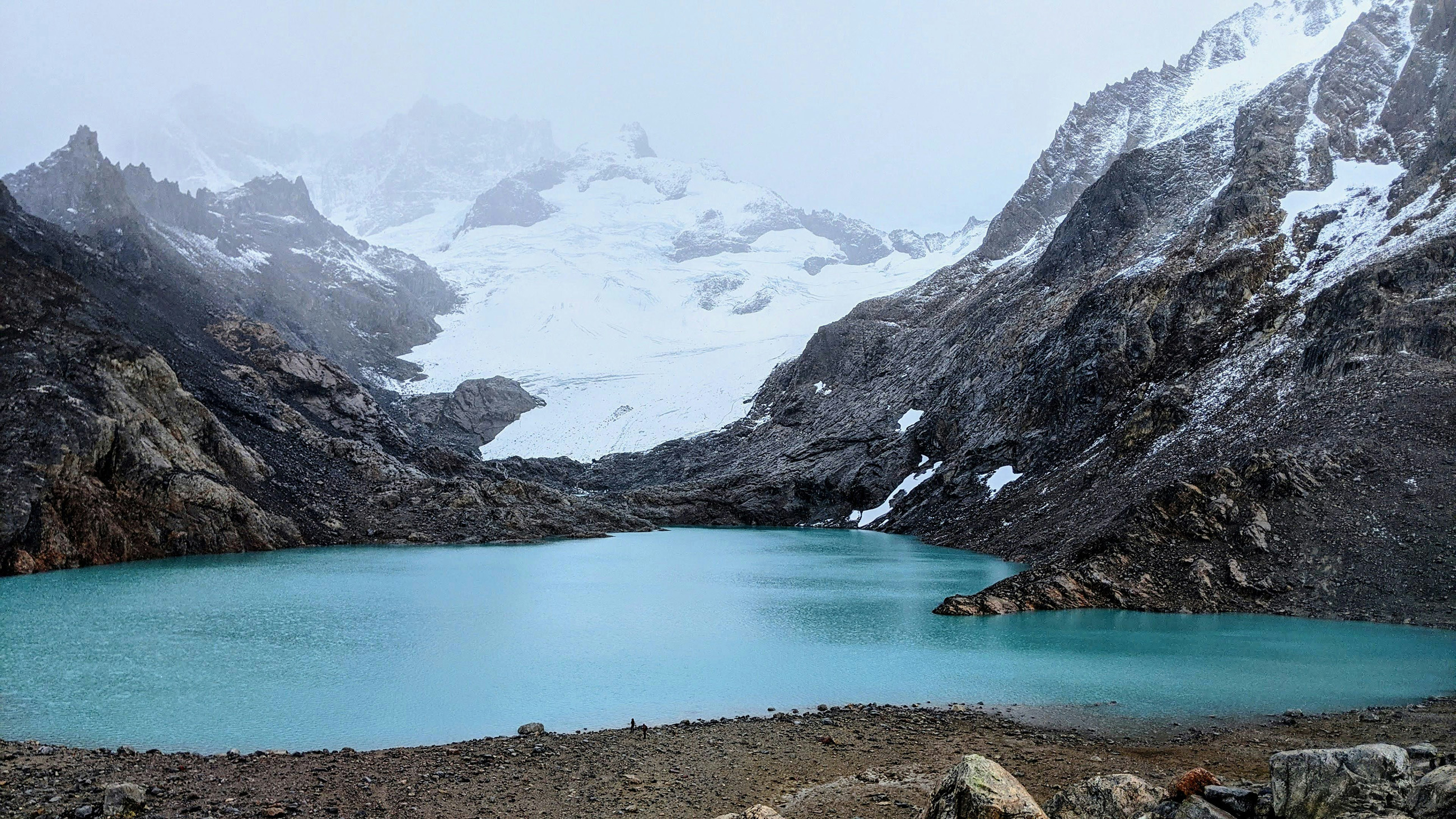 Emerald-colored lake surrounded by mountains, including a glacier, in El Chaltén, Argentina, offering a picturesque location to live in Argentina