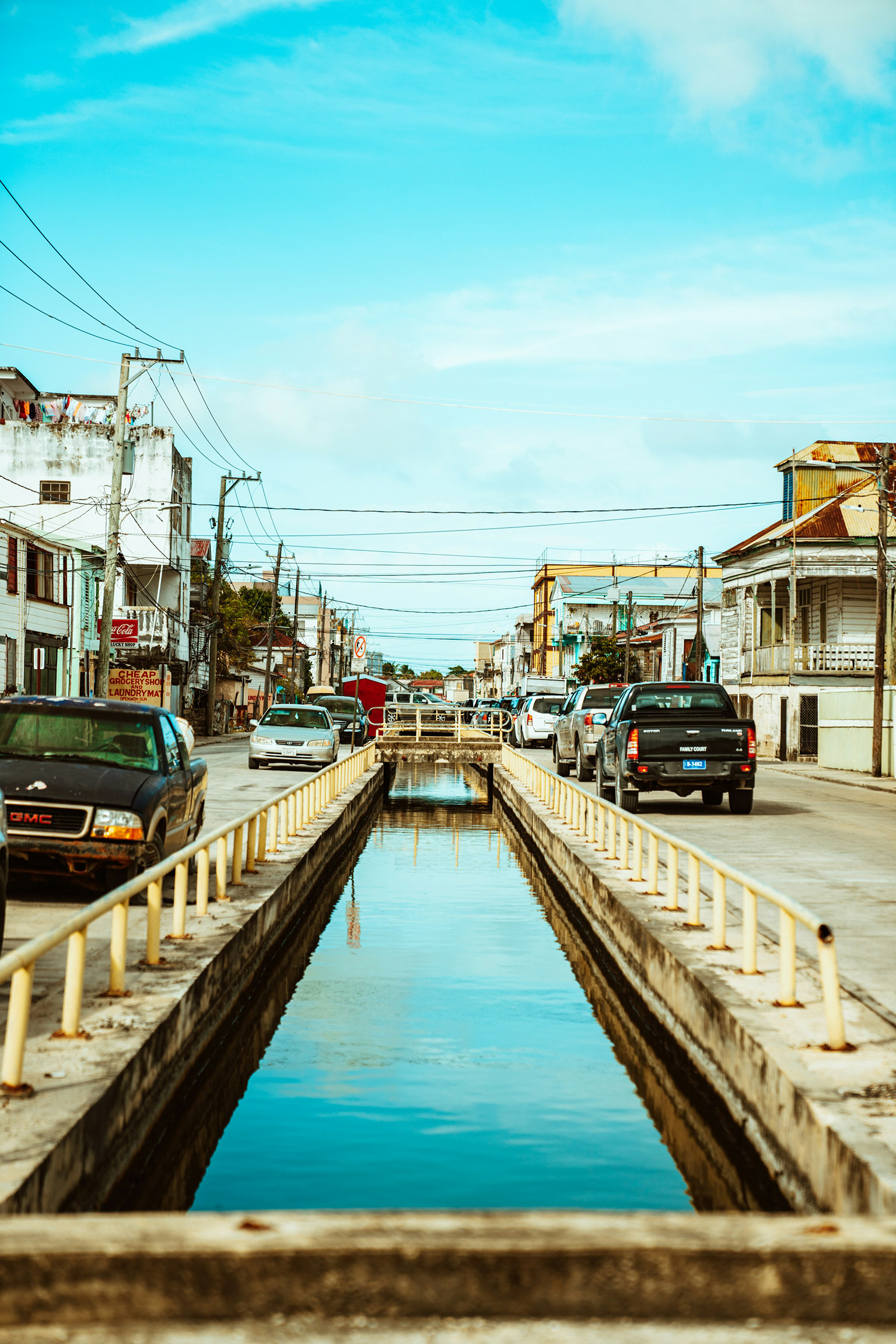 Canal dividing a busy street in Belize City reflecting the urban lifestyle and local culture.