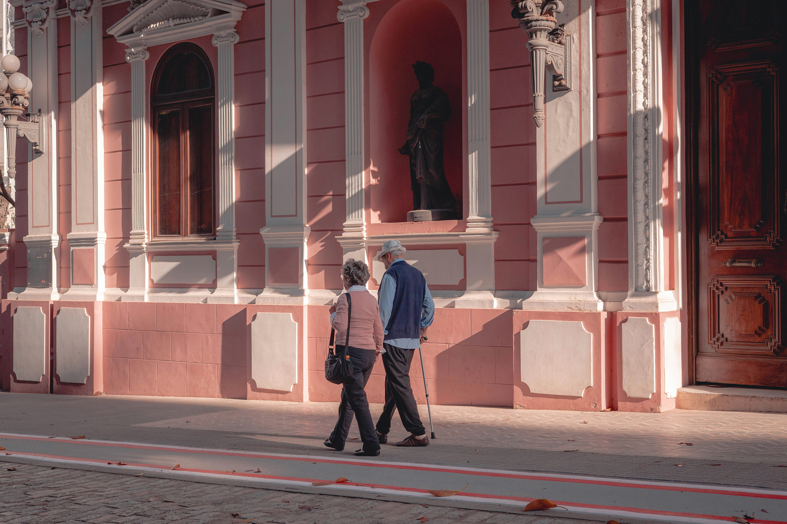 Elderly couple walking together on a calm neighborhood street in Brazil.