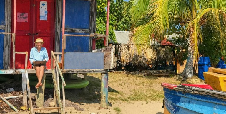 Girl working remotely from Belize on a laptop at a beach shack