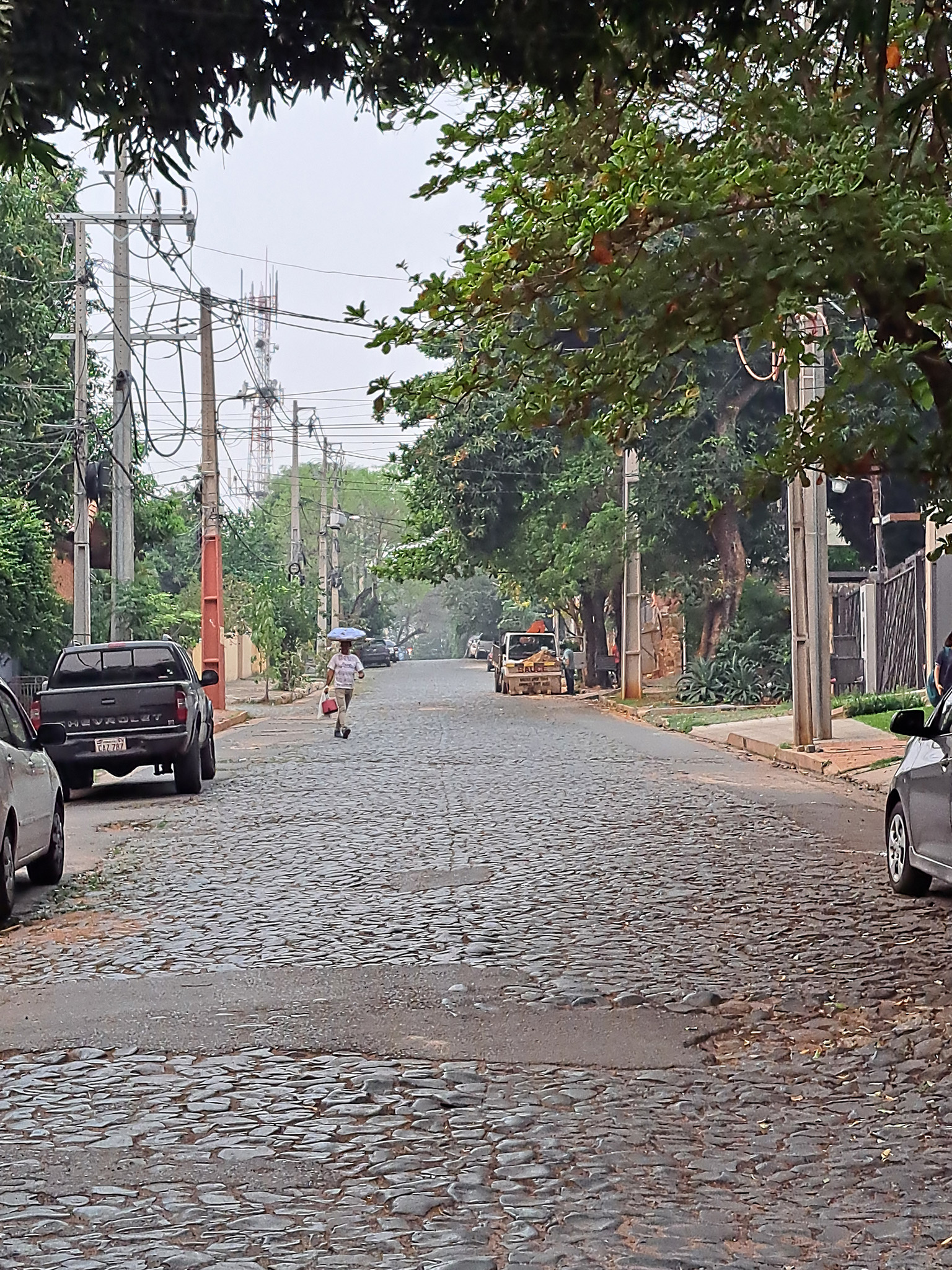 Street vendor carrying chipa on his head along a cobbled street in Mburcuya, one of the neighborhoods to live in Asunción