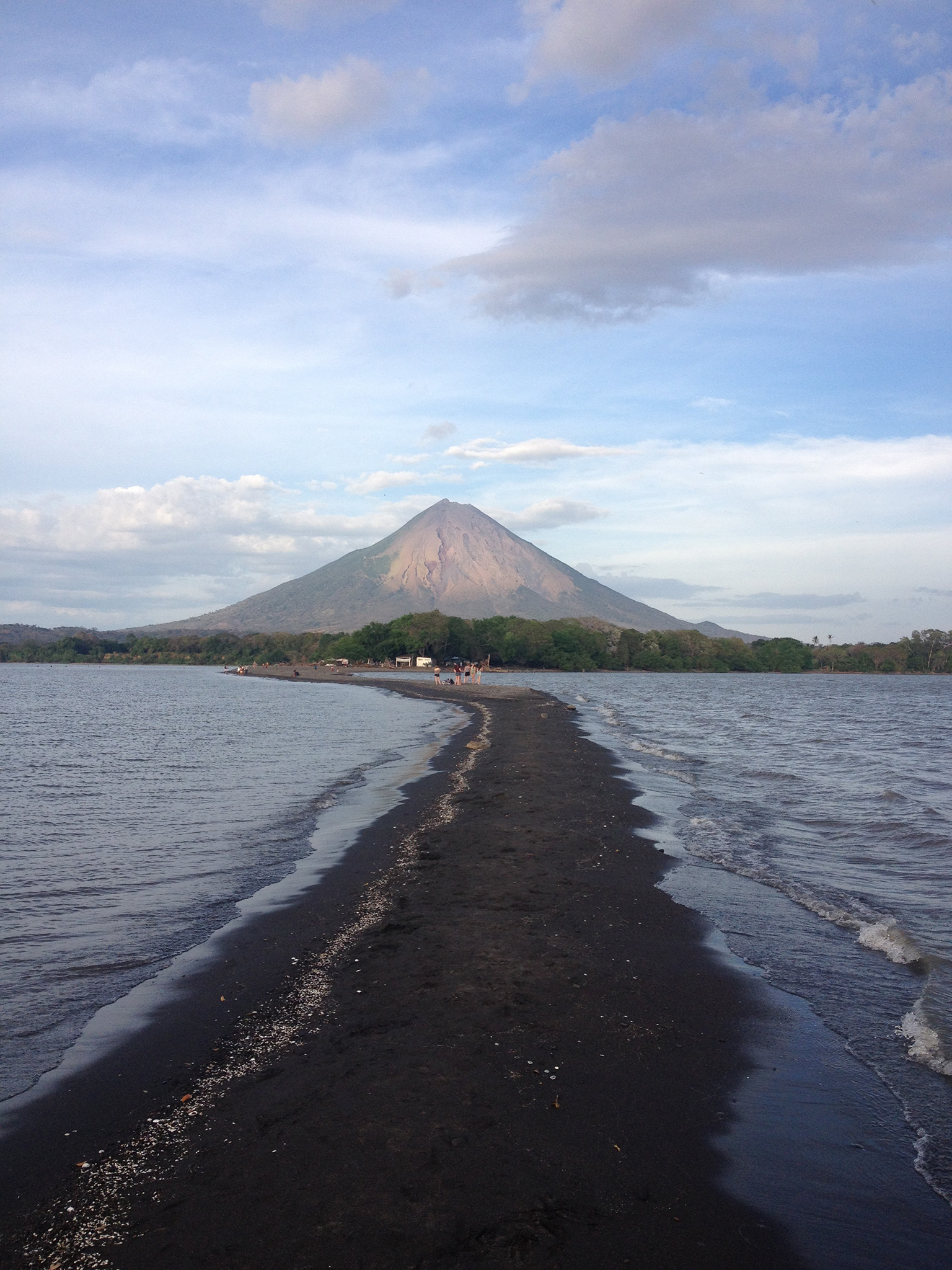 Trail of black volcanic sand with a volcano in the distance in Nicaragua