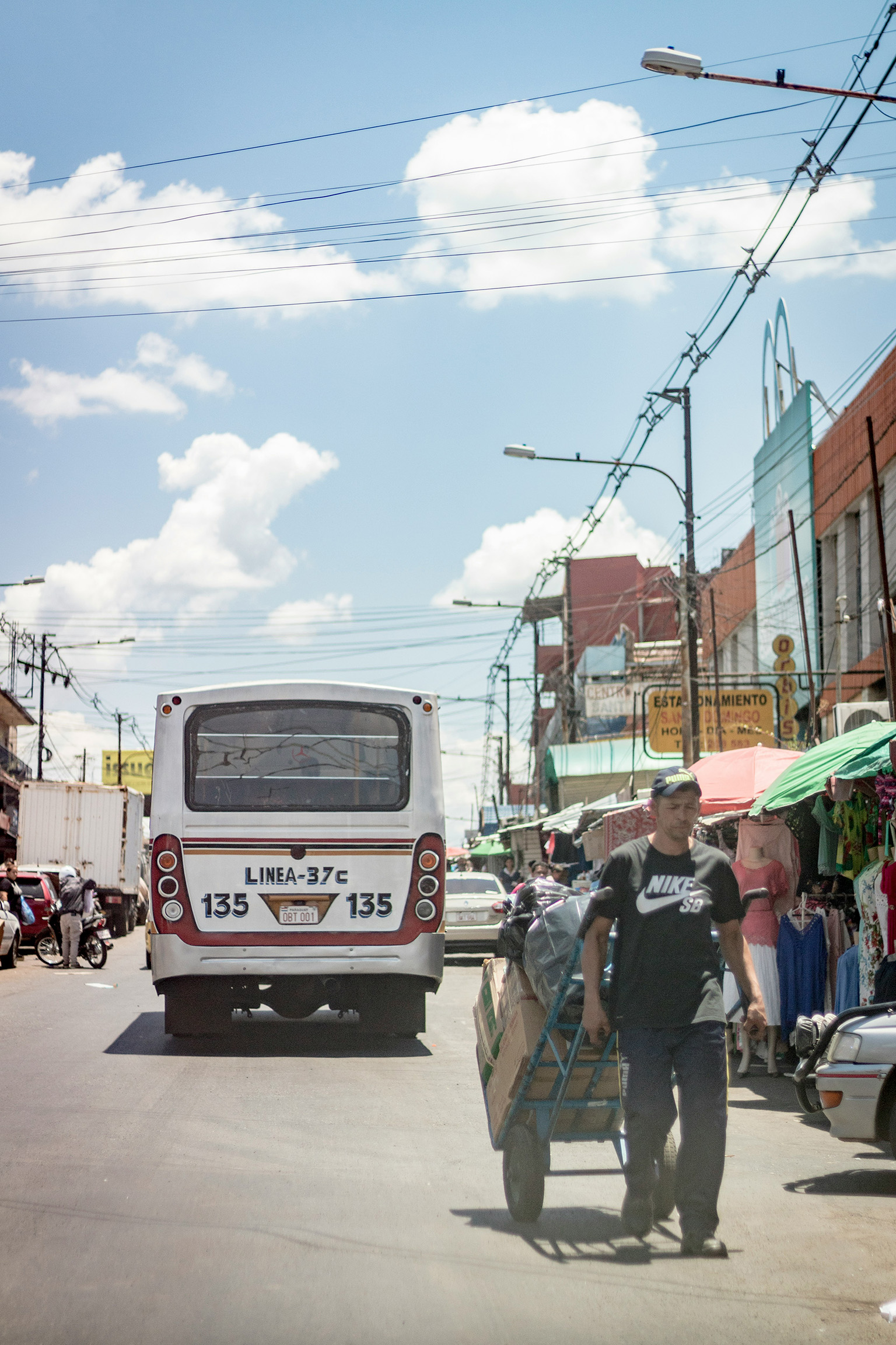 : Busy street in Paraguay with a bus and a man hauling goods