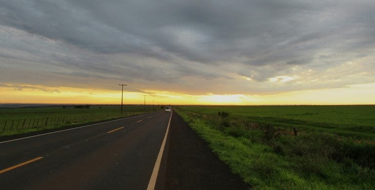 Paved highway in Paraguay with grassy fields and stormy sky, illustrating living in Paraguay pros and cons