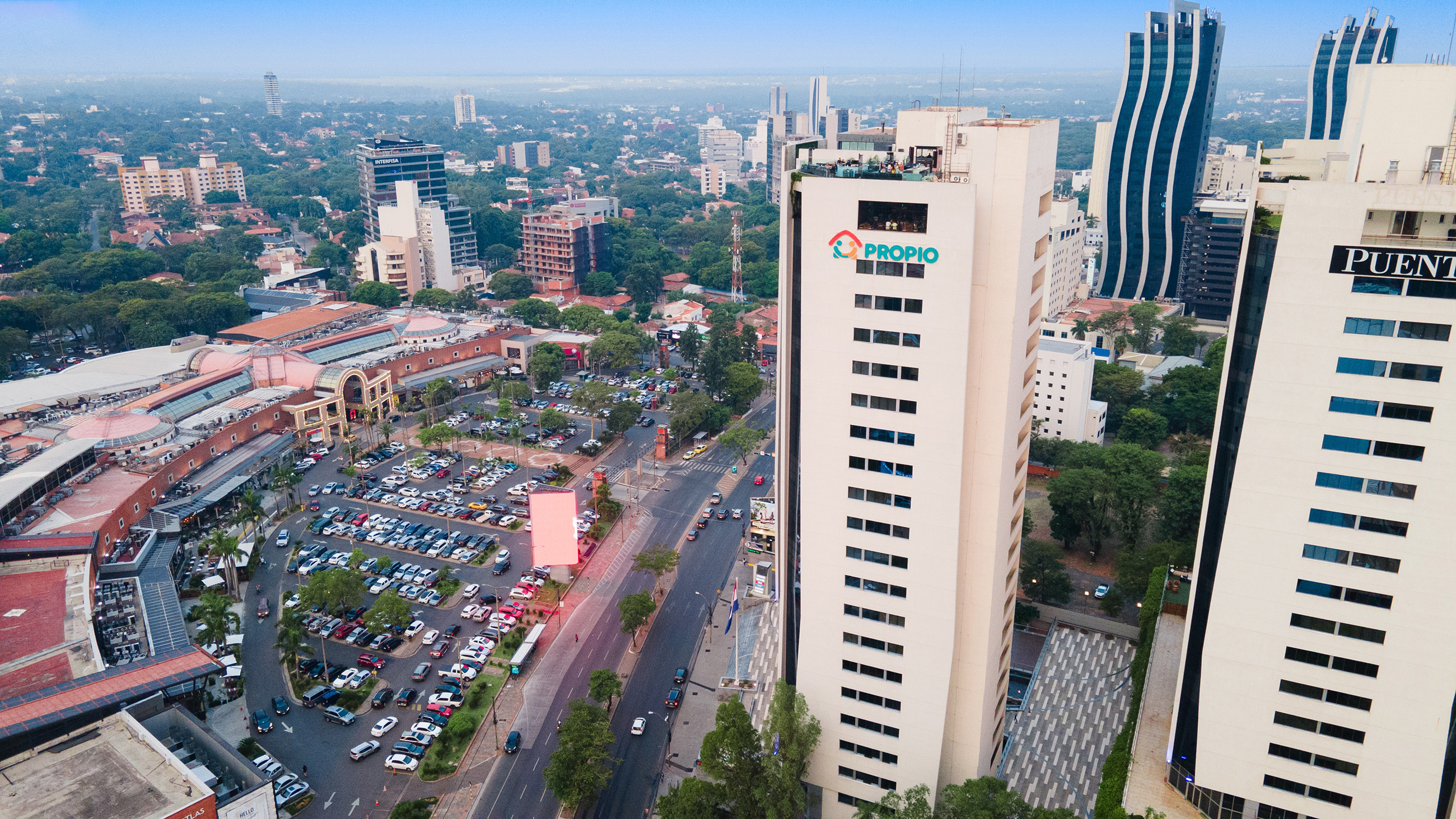 Aerial view of Shopping Del Sol Mall in a neighborhood in Asunción, with its parking lot and nearby tall buildings in the bustling area