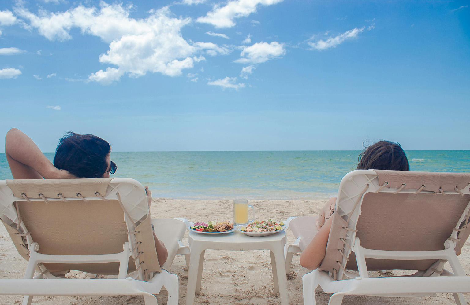 Couple relaxing on oceanfront lounge chairs in Belize during retirement