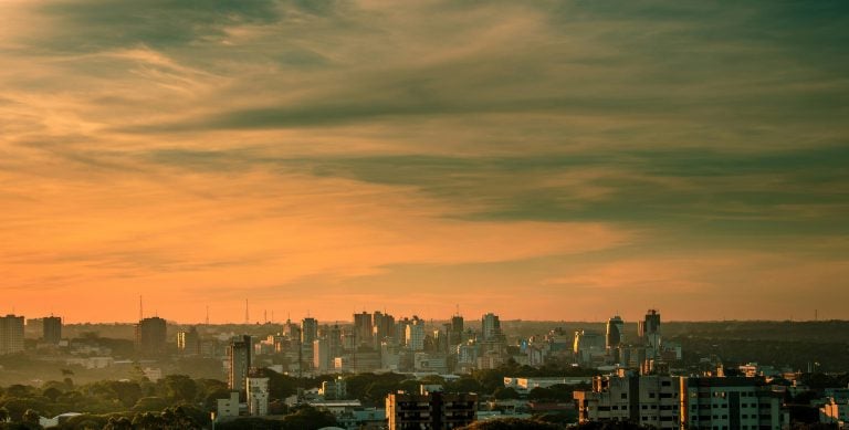 Skyline of ciudad del este paraguay at sunset with high-rise buildings glowing over the Paraná River.
