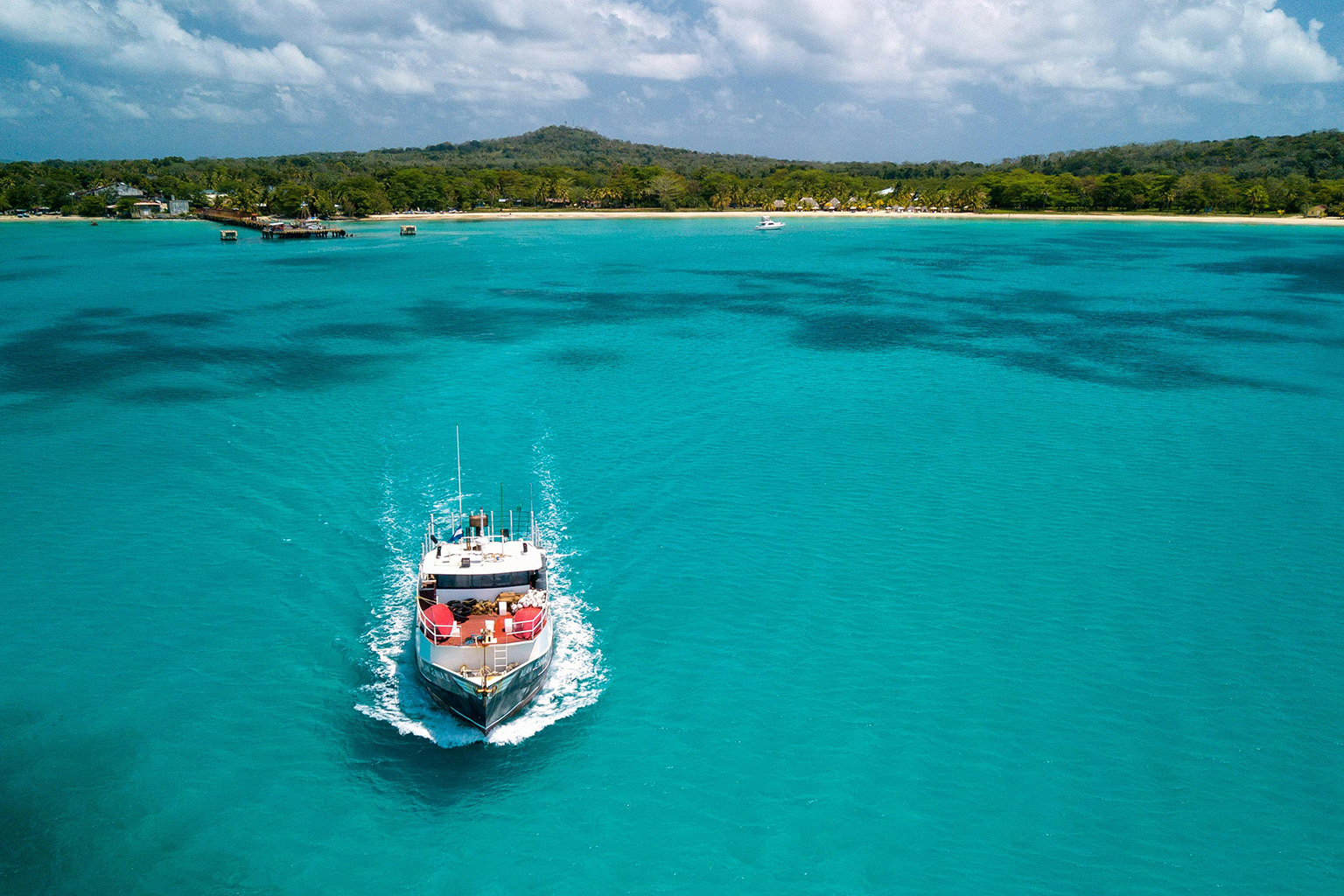 Big Corn Island turquoise water with water taxi in view, ideal for remote work in the Corn Islands Nicaragua