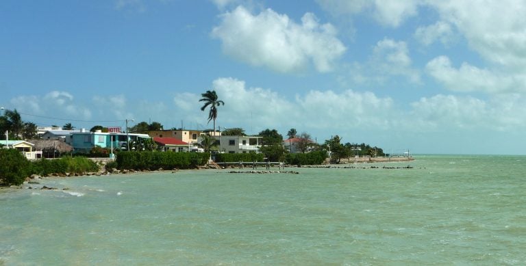 Corozal Belize coastal homes with turquoise water and palm trees showing the relaxed lifestyle of living in Corozal Belize