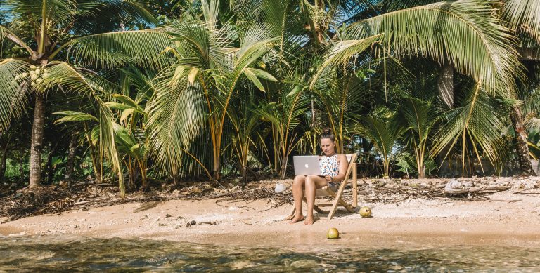Digital nomad working remotely in the Corn Islands Nicaragua on a lounge chair by the beach with lush jungle behind