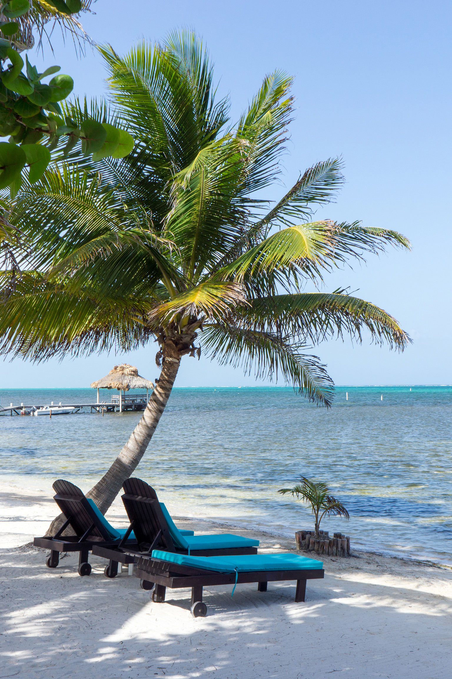 This tranquil Belize beach scene with loungers and umbrellas reflects the country’s relaxed coastal lifestyle.
