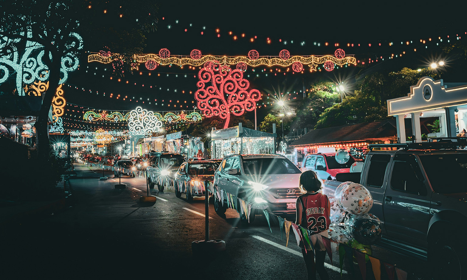 Street in Nicaragua decorated for Christmas with child walking along sidewalk at night