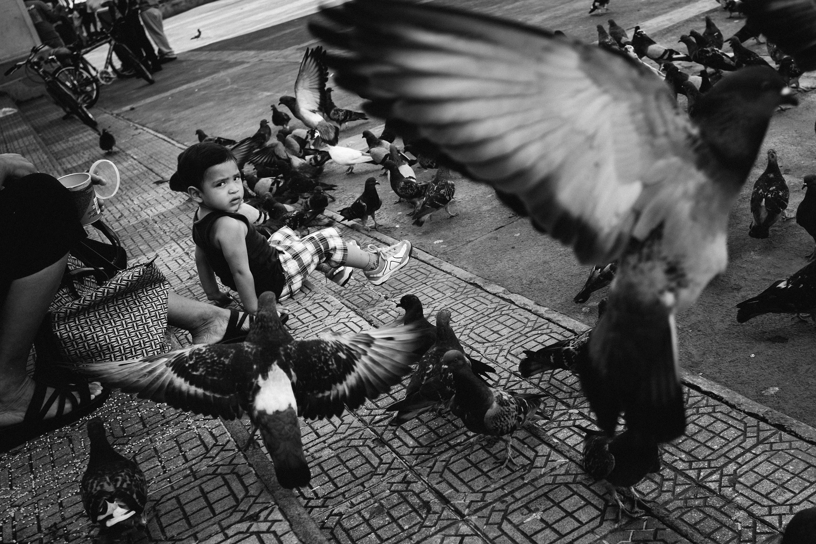 leon-town-square-girl-pigeons-nicaragua Young girl feeding pigeons in León’s town square — everyday local life in one of the authentic places where expats live in Nicaragua