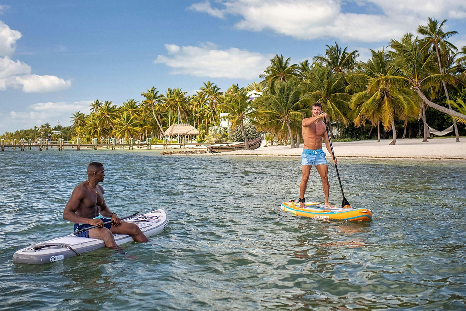 Living in Belize with two people paddle boarding on calm Caribbean waters