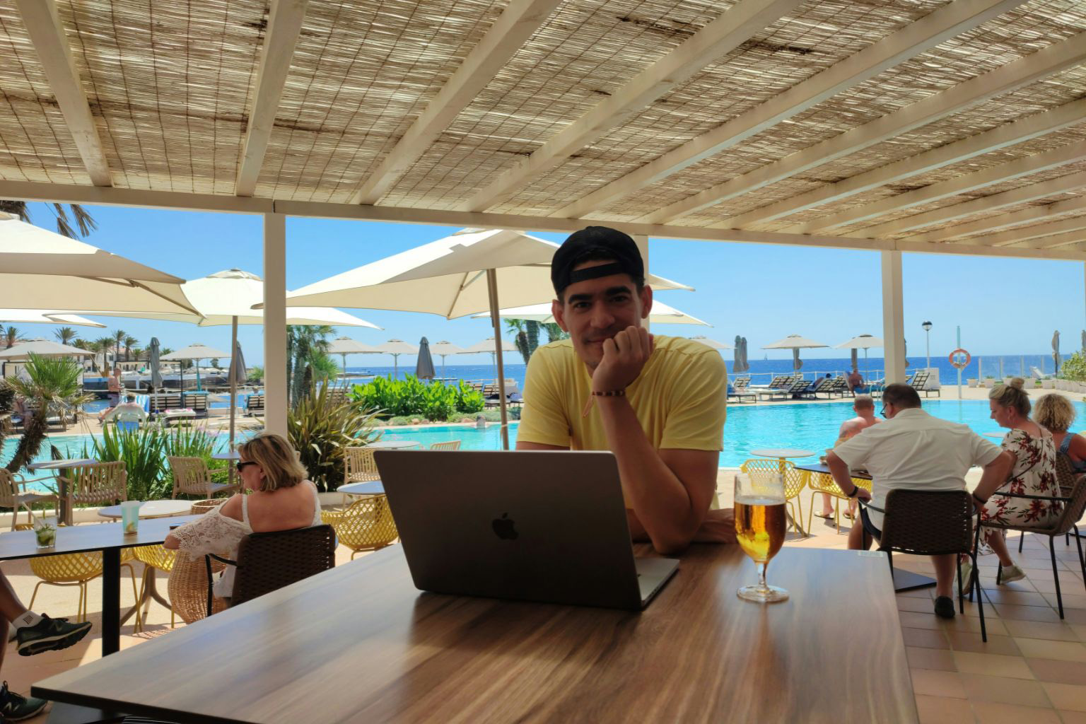 Expat working on laptop in a Belize restaurant with ocean view and pool
