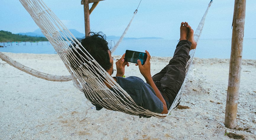 Digital nomad working on phone in hammock on the beach living in Nicaragua
