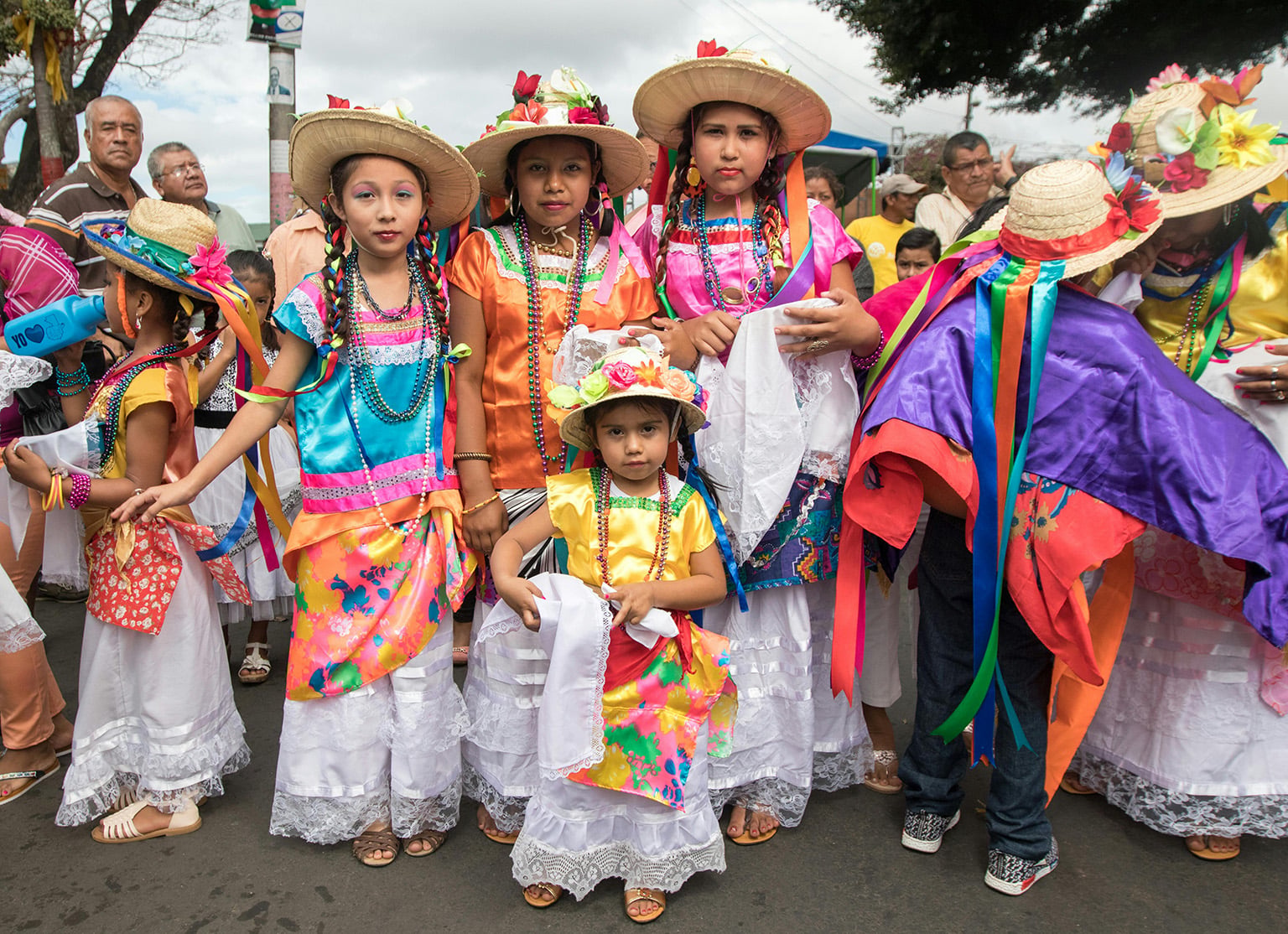 Girls wearing vibrant, colorful traditional folklore costumes at a street parade, showcasing the cultural heritage of living in Nicaragua