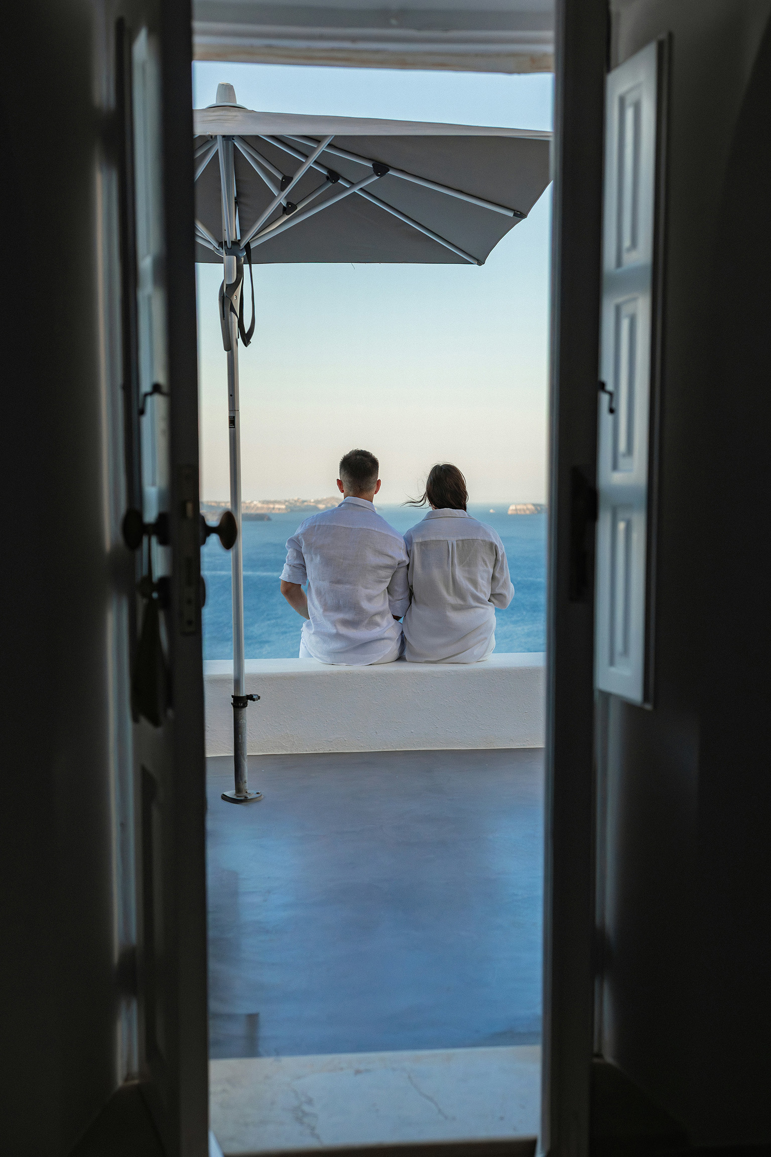 A couple on an oceanfront deck looking out at the sea, illustrating how far your money goes in Paraguay vs Belize vs Nicaragua.