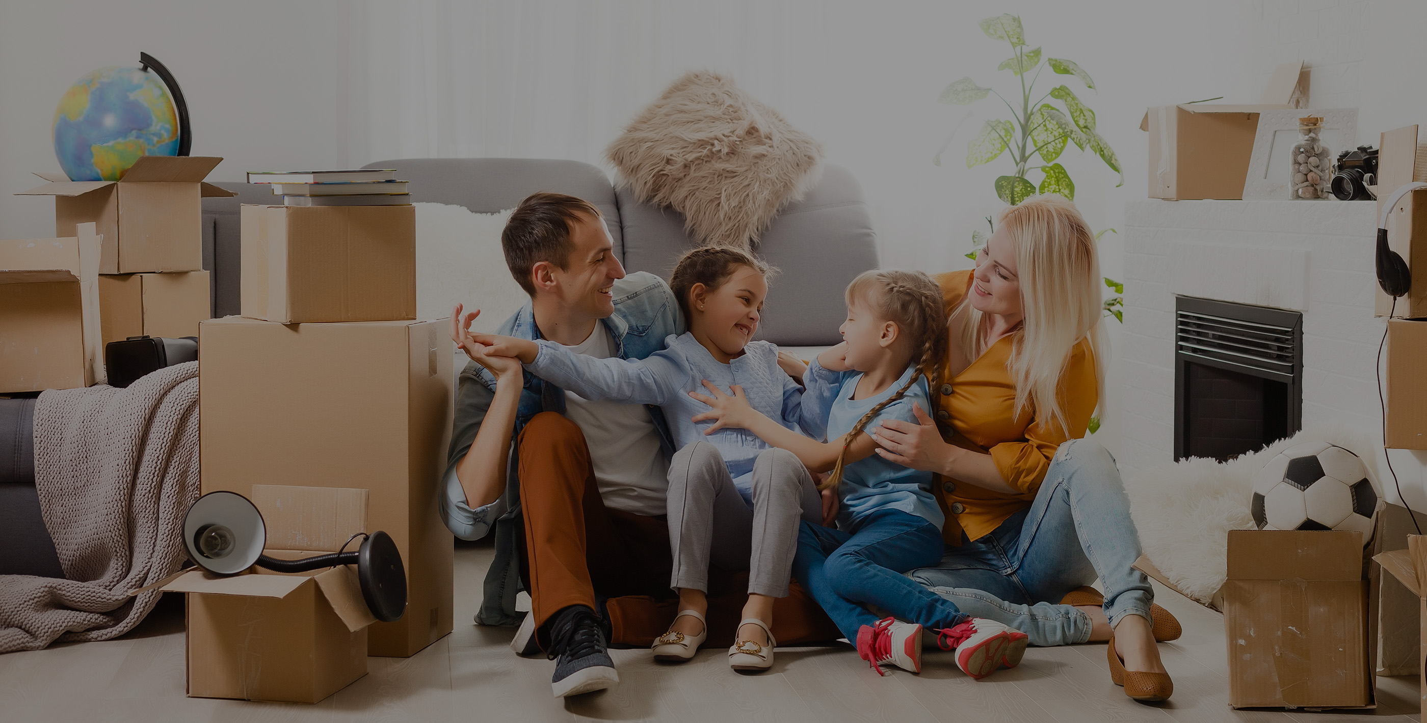 Young family taking a break while shipping belongings to Paraguay, surrounded by packing boxes