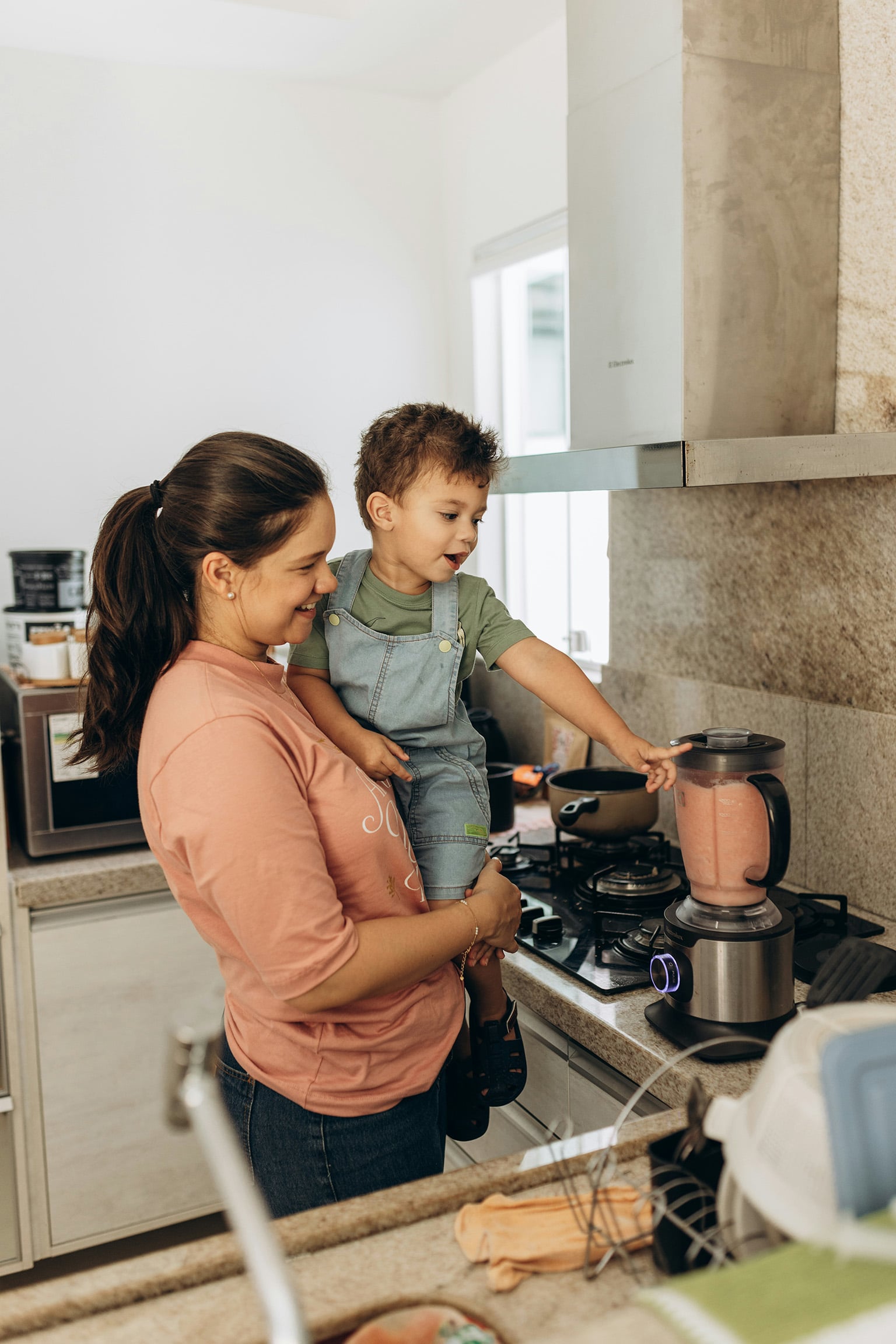 underestimating-voltage-differences-paraguay-blender Woman holding her child in the kitchen using a blender, illustrating the risk of underestimating voltage differences in Paraguay