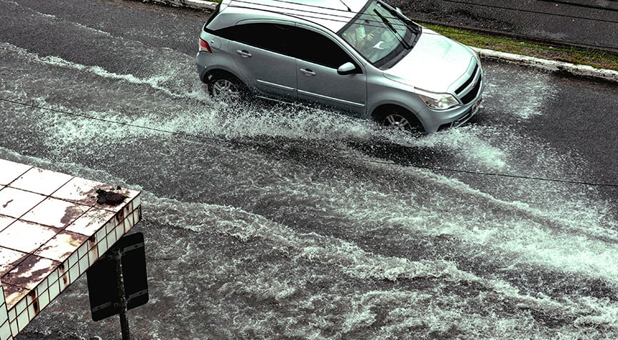 Car driving through a flooded street, highlighting infrastructure challenges when living in Paraguay