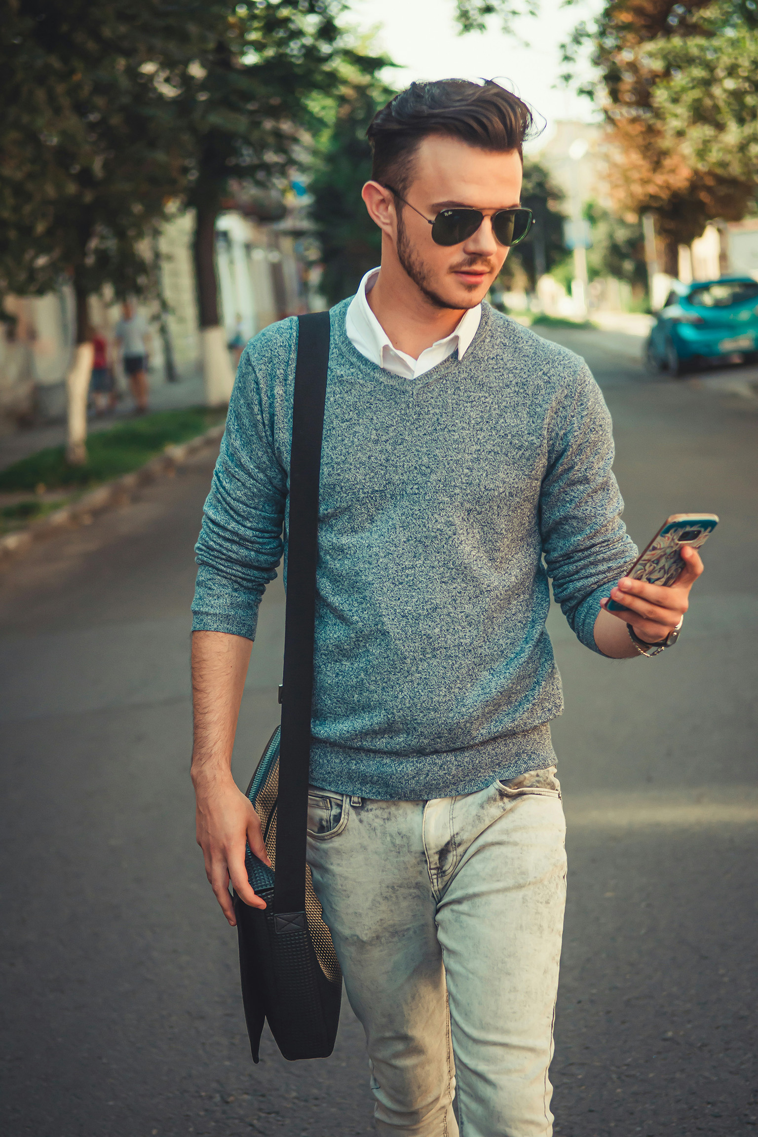 Man walking while looking at his phone and distracted from his surroundings