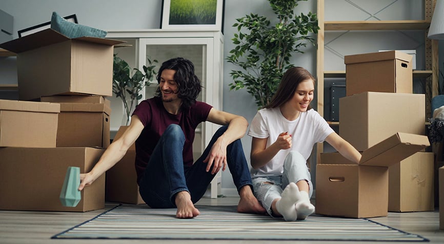 Couple unpacking moving boxes on their living room floor after relocating and living in Paraguay